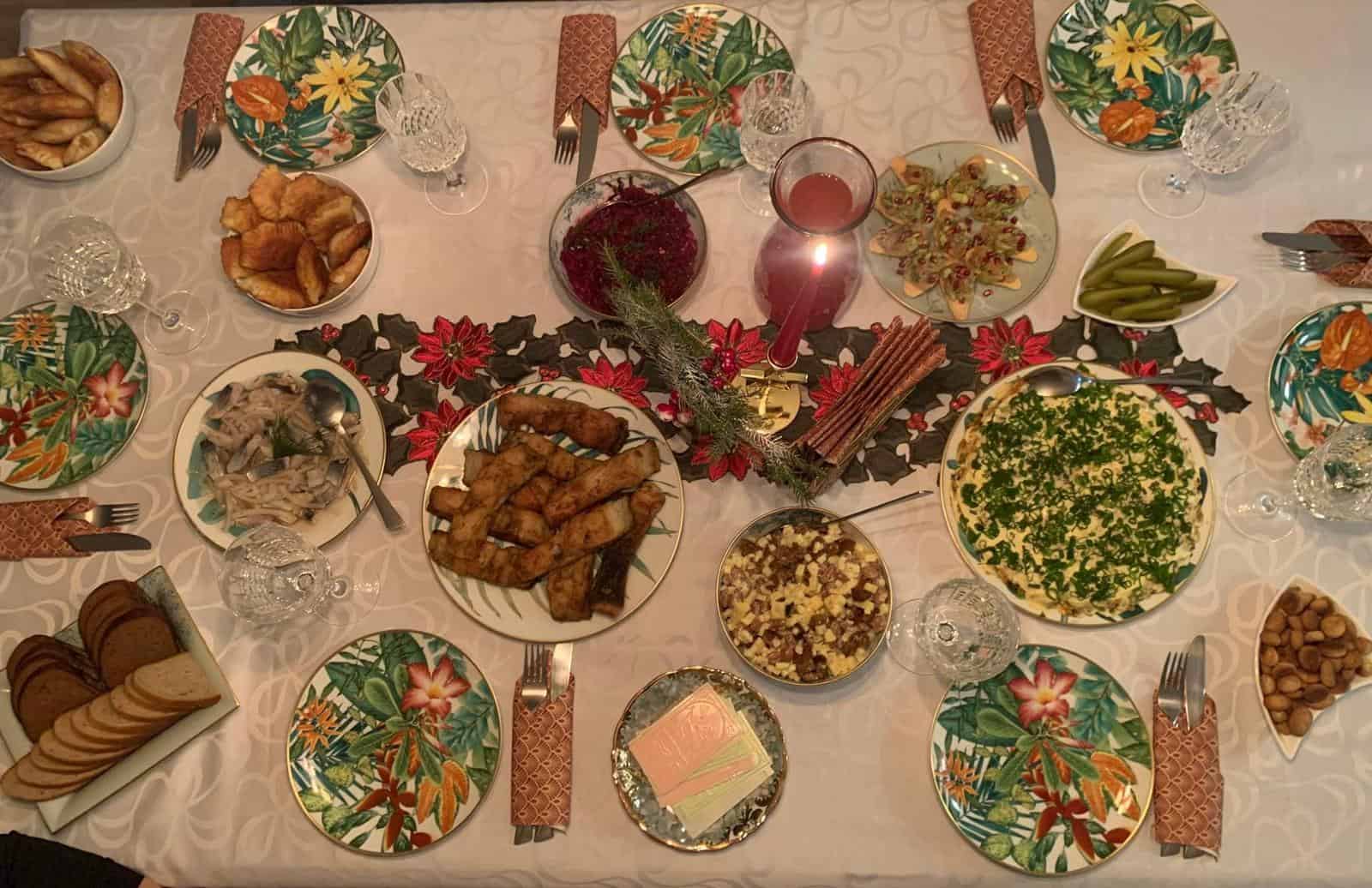 image depicts a traditional Lithuanian Christmas Eve dinner, known as Kūčios