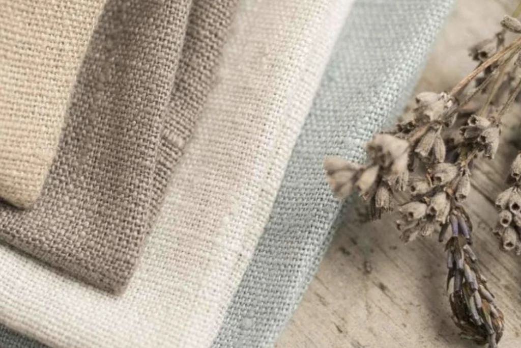 Natural linen fabrics in neutral colors displayed with dried flowers.