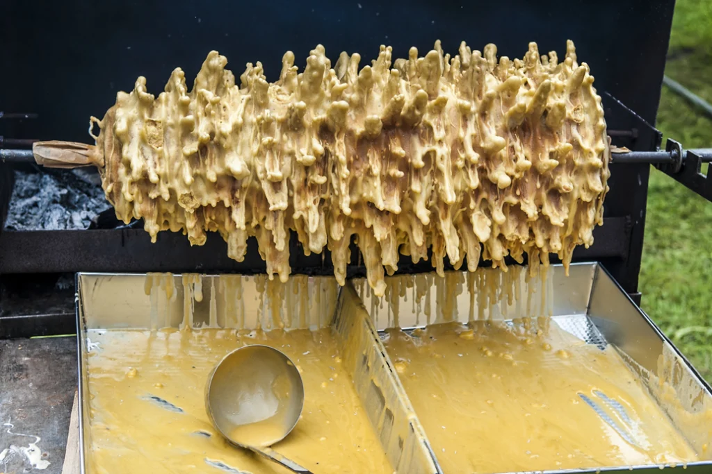 Šakotis tree cake cooking on a rotating spit with dripping batter.