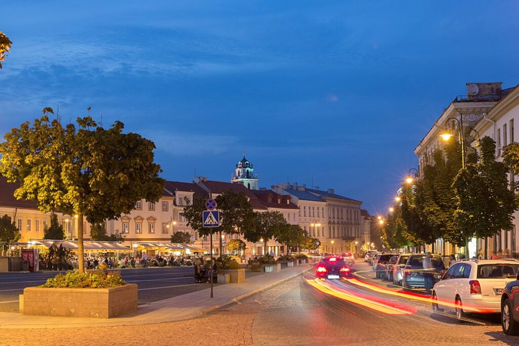Historic Vilnius Old Town street with restaurants and evening lights.
