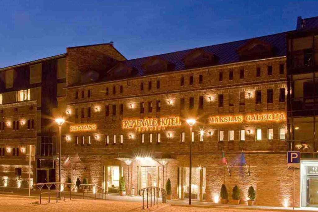 Illuminated Promenade Hotel building in Liepāja, Latvia, at night.