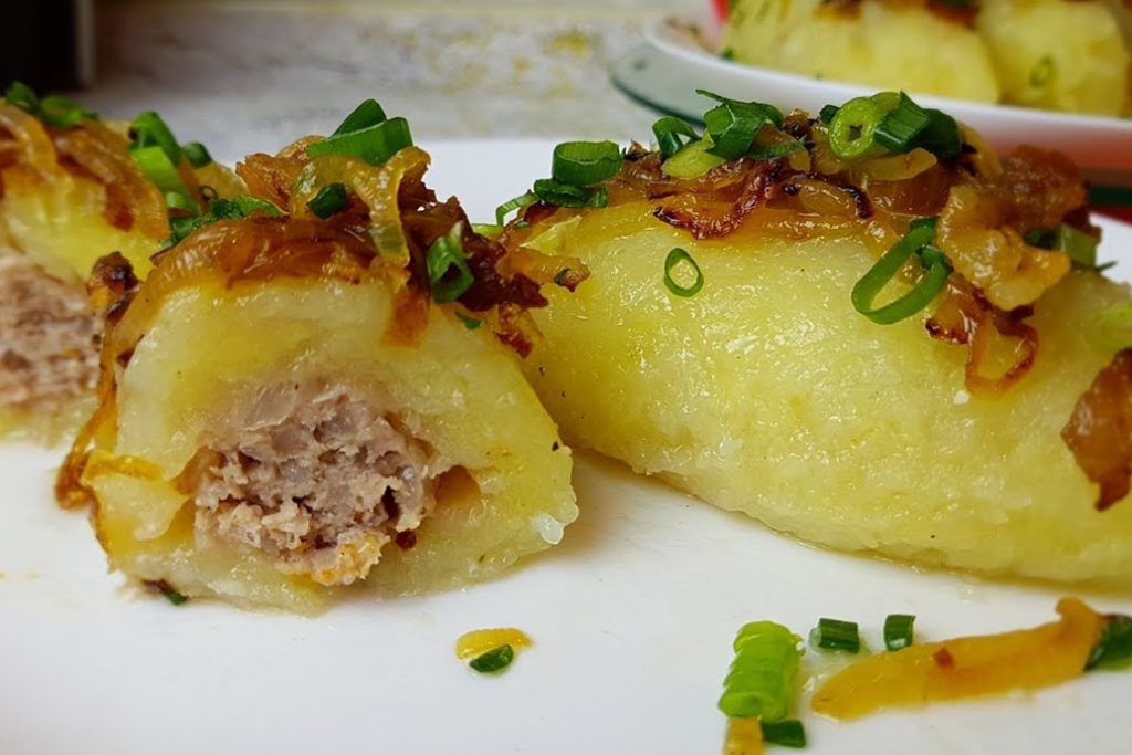 Traditional Lithuanian cepelinai stuffed potato dumplings with meat and fried onions.