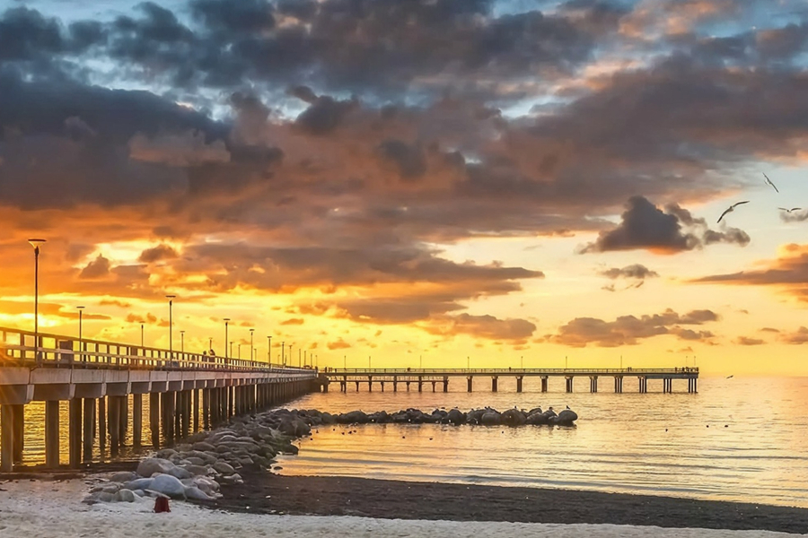 Beautiful sunset over the Baltic Sea with a long pier extending into the water.