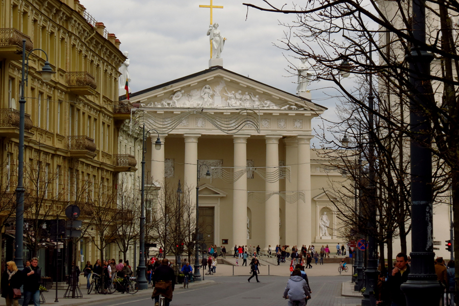 Vilnius Cathedral viewed from a historic street with pedestrians.