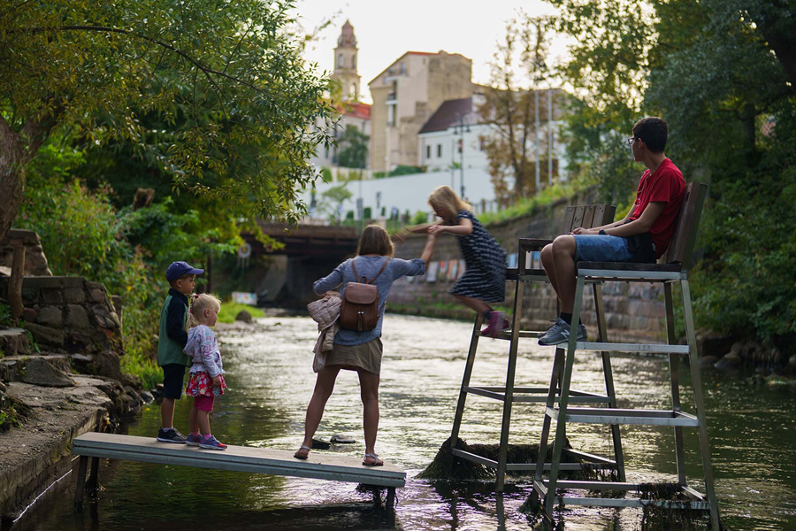 Family enjoying a peaceful riverside spot in Vilnius, Lithuania.