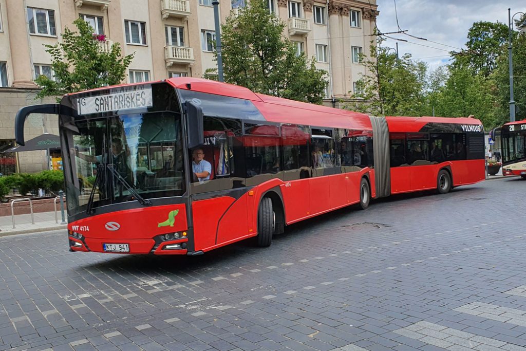 Modern red bus and trolleybus on a street in Vilnius.