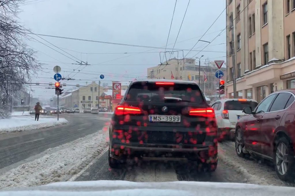 Cars navigating a snowy street in Riga, Latvia.