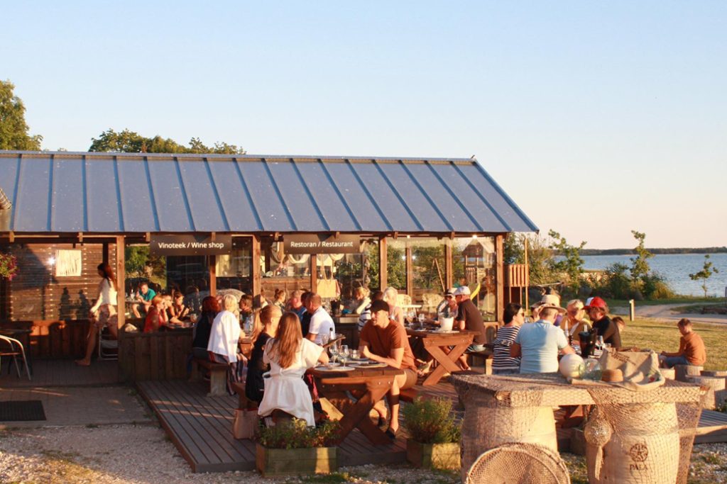 Tourists dining at an outdoor waterfront restaurant.