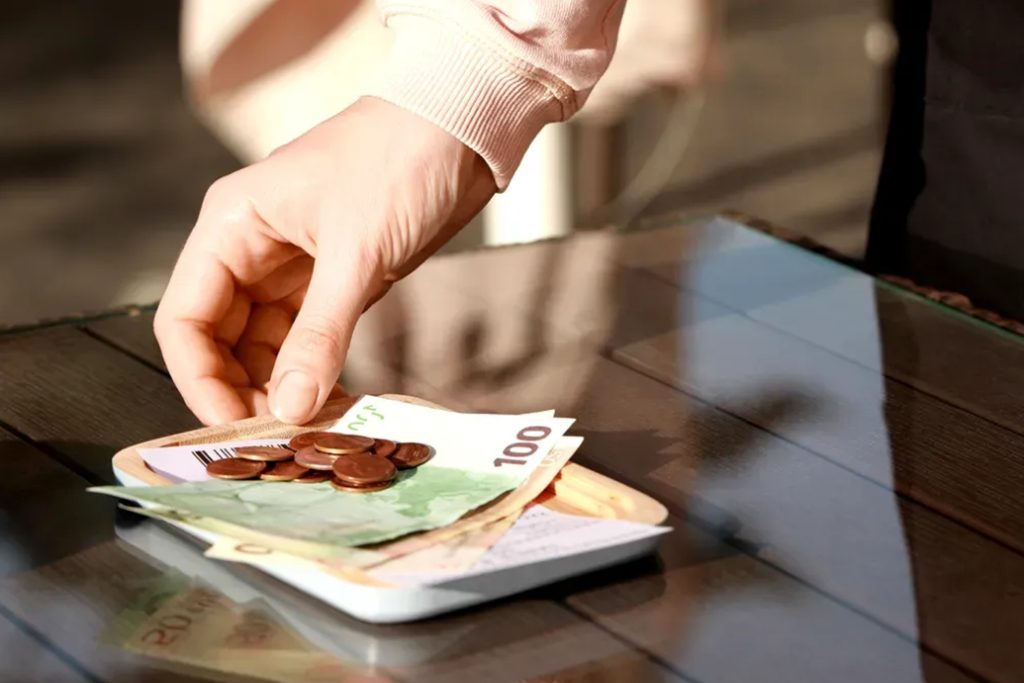 Person leaving euro banknotes and coins as a tip.