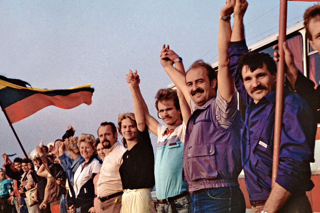 People holding hands beside a Lithuanian flag during the Baltic Way.