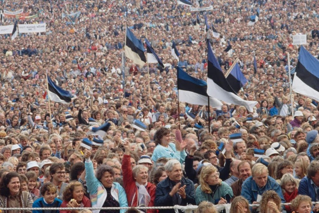 Large crowd waving Estonian flags at a historic independence rally.